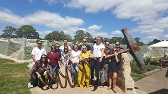 Group of happy people posing with a giant corkscrew sculpture at a winery